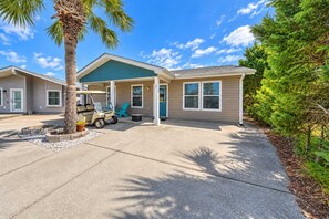 A two-story house with a covered porch, a driveway, and a golf cart.