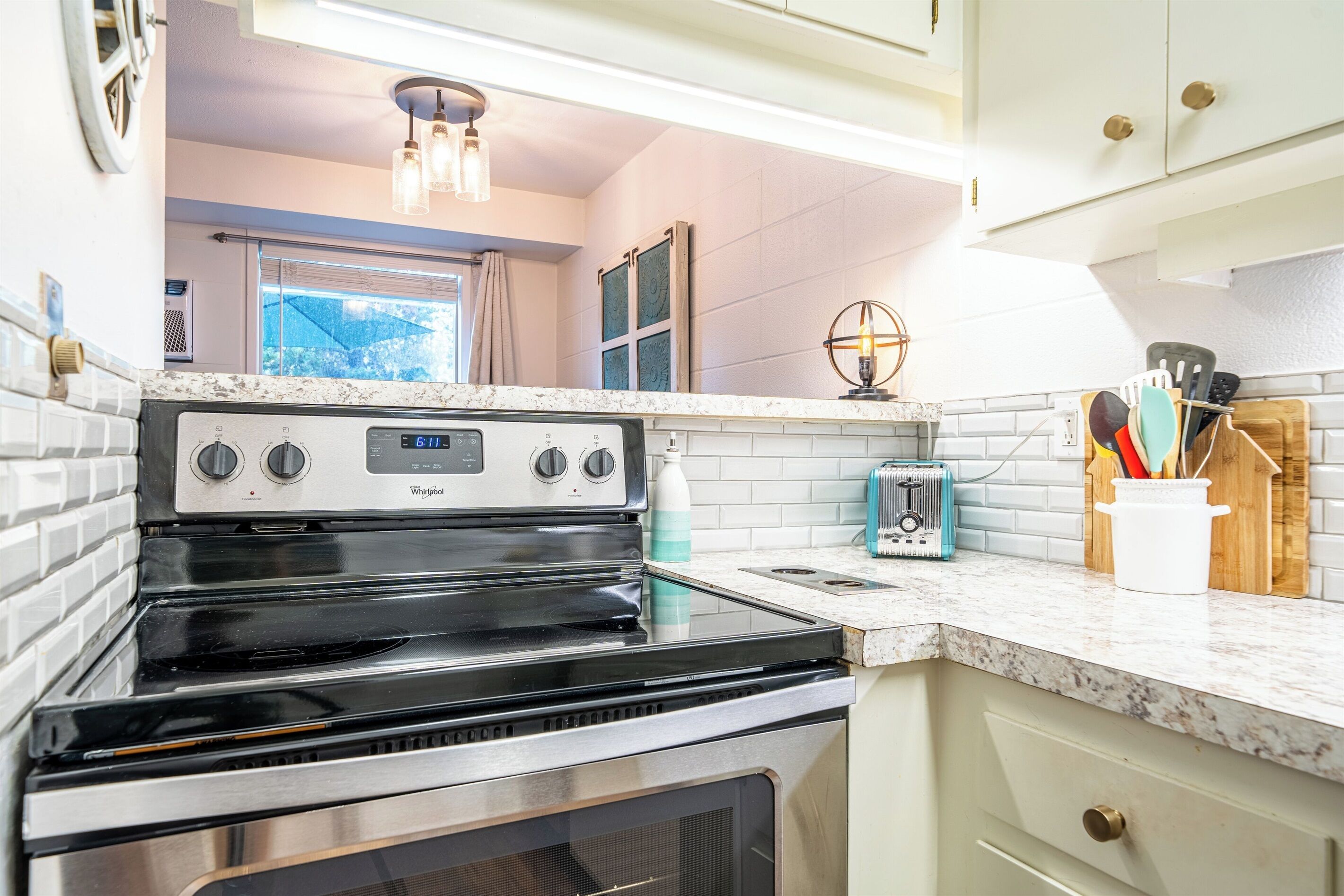 A kitchen with a stainless steel stove, white cabinets, and a window with a view.