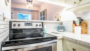 Une cuisine équipée d’une cuisinière en acier inoxydable, de meubles blancs et d’une fenêtre offrant une belle vue.