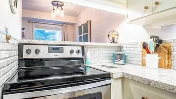 A kitchen with a stainless steel stove, white cabinets, and a window with a view.