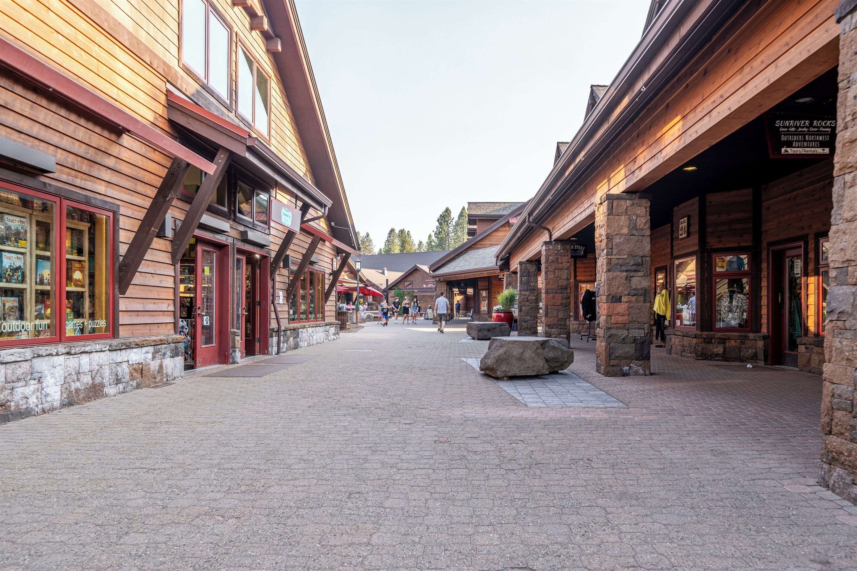 A cobblestone street lined with wooden buildings, some with stone pillars, and a few people walking.