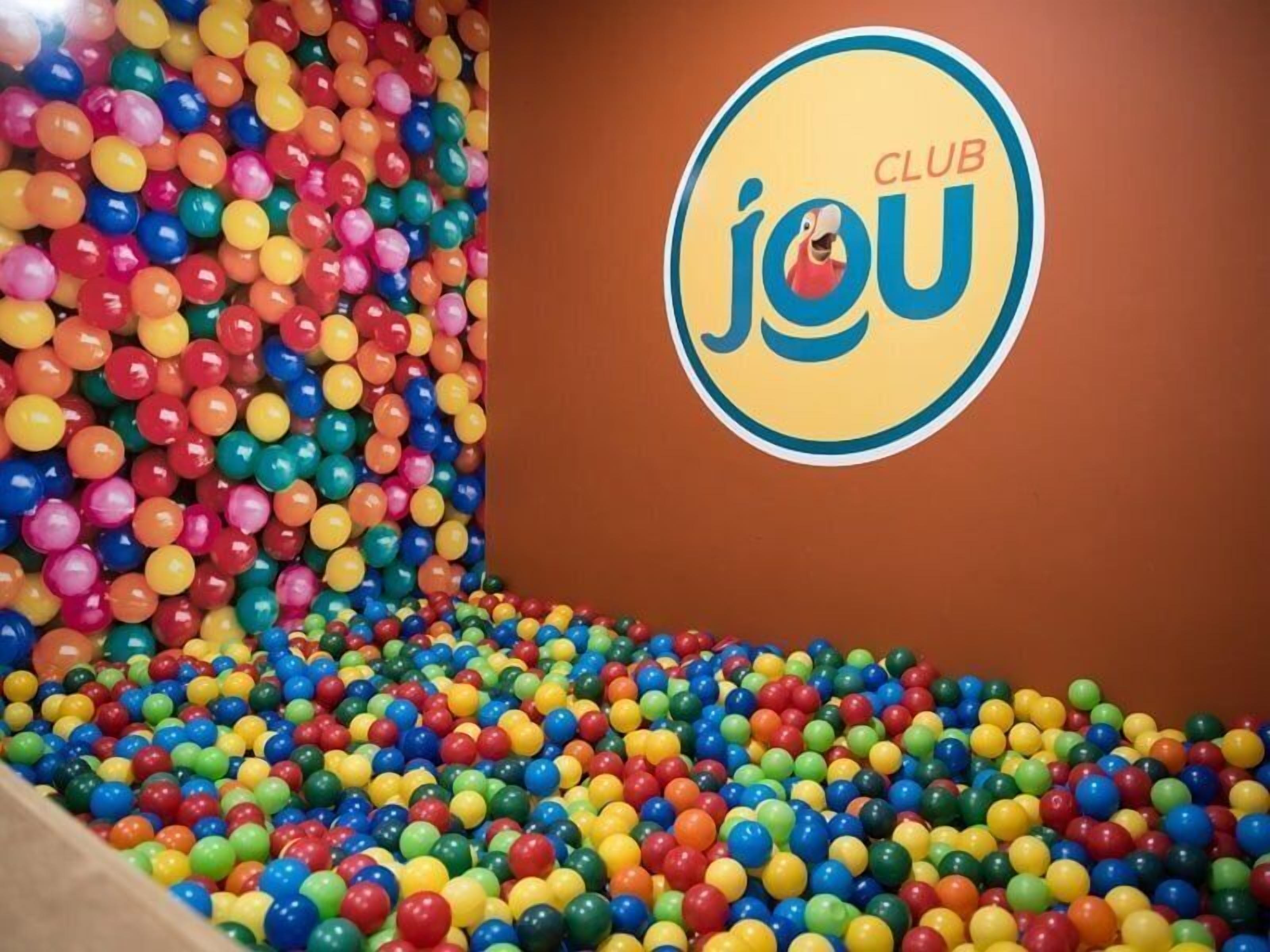 A colorful ball pit with a logo on the wall.