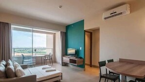 Une chambre d’hôtel moderne dotée d’un balcon, d’un canapé, d’une table à manger et d’un téléviseur.