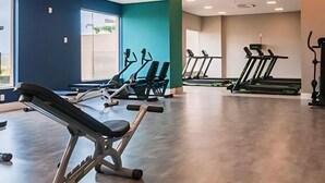 Une salle de sport équipée de matériel d’exercice, dotée de grandes fenêtres et présentant un design moderne.