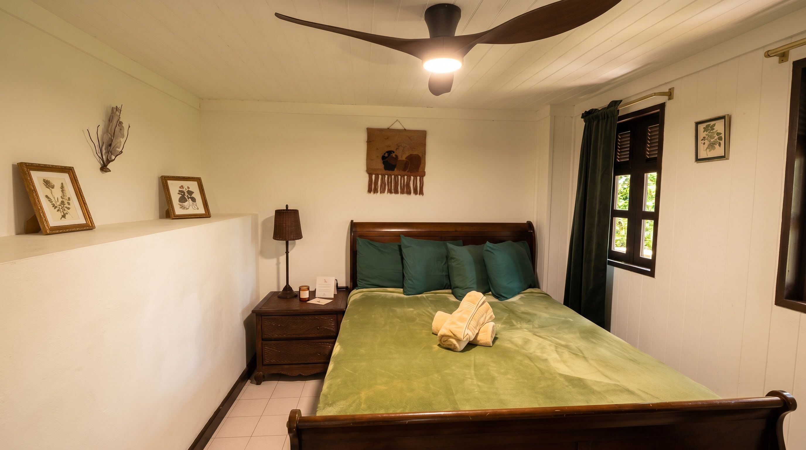 A bedroom with a bed, nightstand, lamp, and ceiling fan.