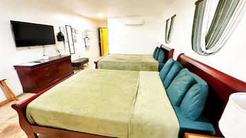 A hotel room with two beds, a TV, a dresser, and a window with curtains.
