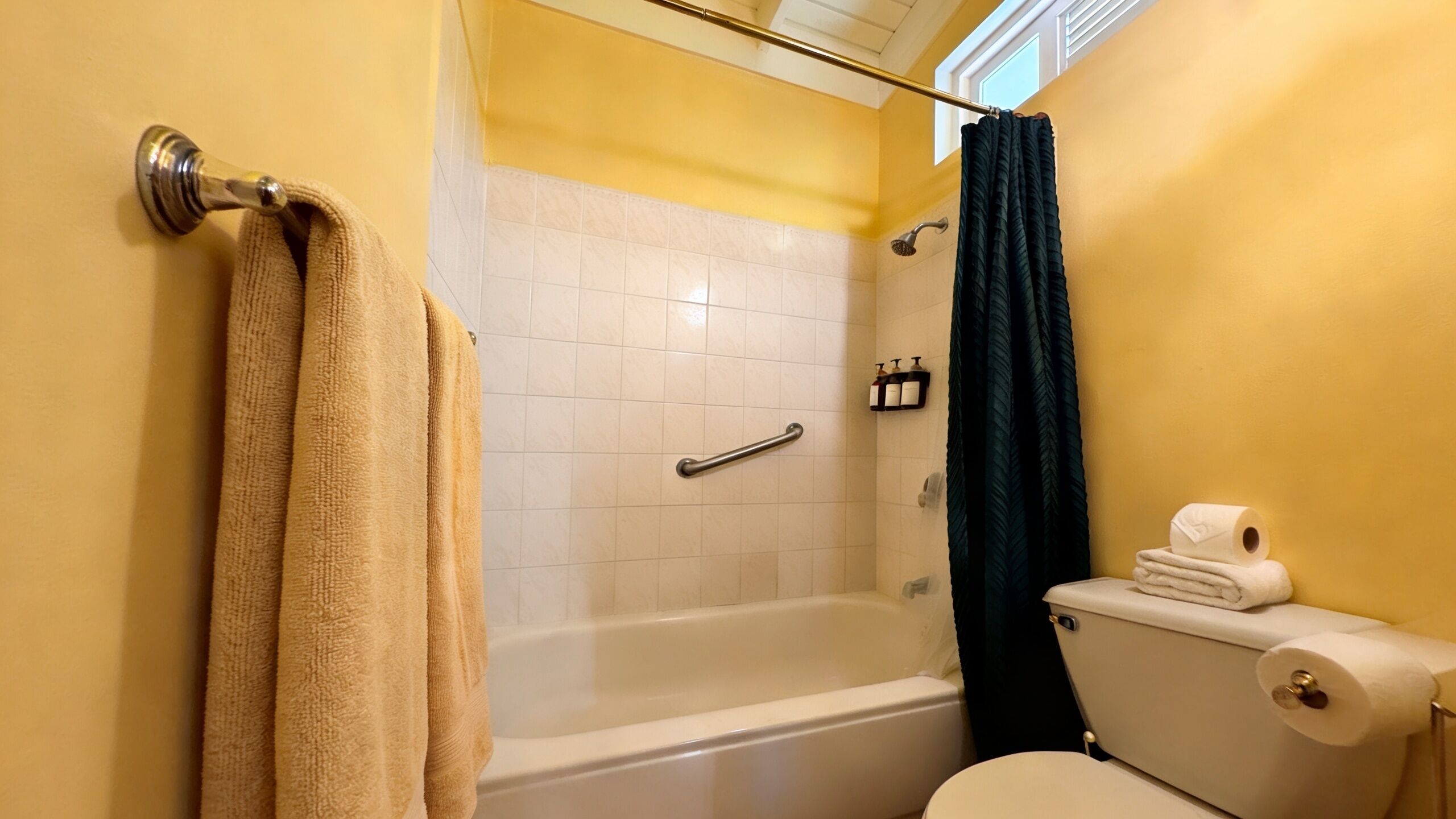 A bathroom with a bathtub, toilet, and towel rack.