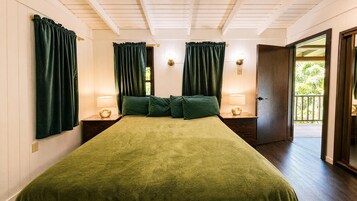 Un dormitorio con cubrecama verde, dos lámparas de noche y una puerta que da a un espacio exterior.