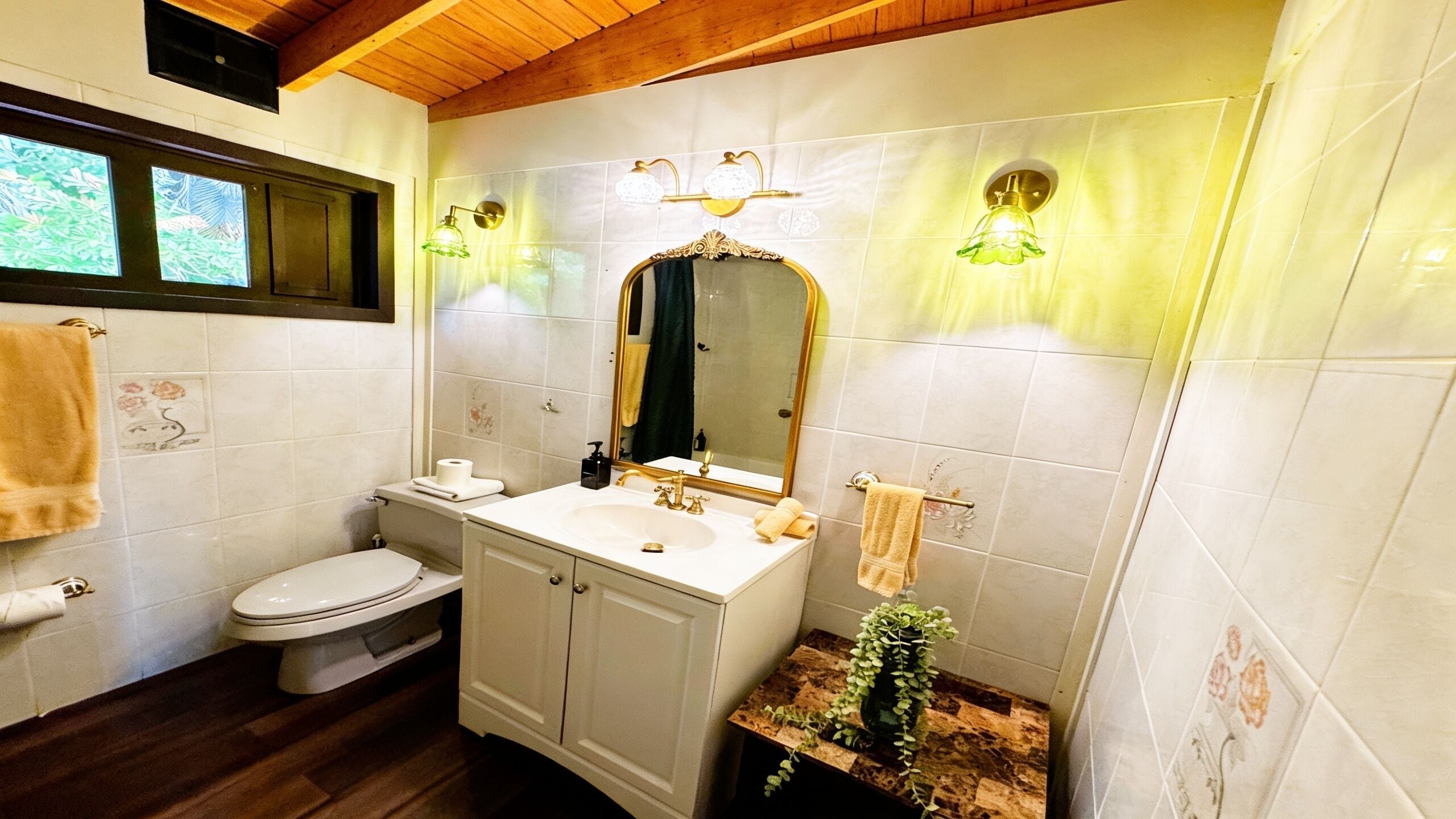 A bathroom with a toilet, sink, mirror, and towel rack.