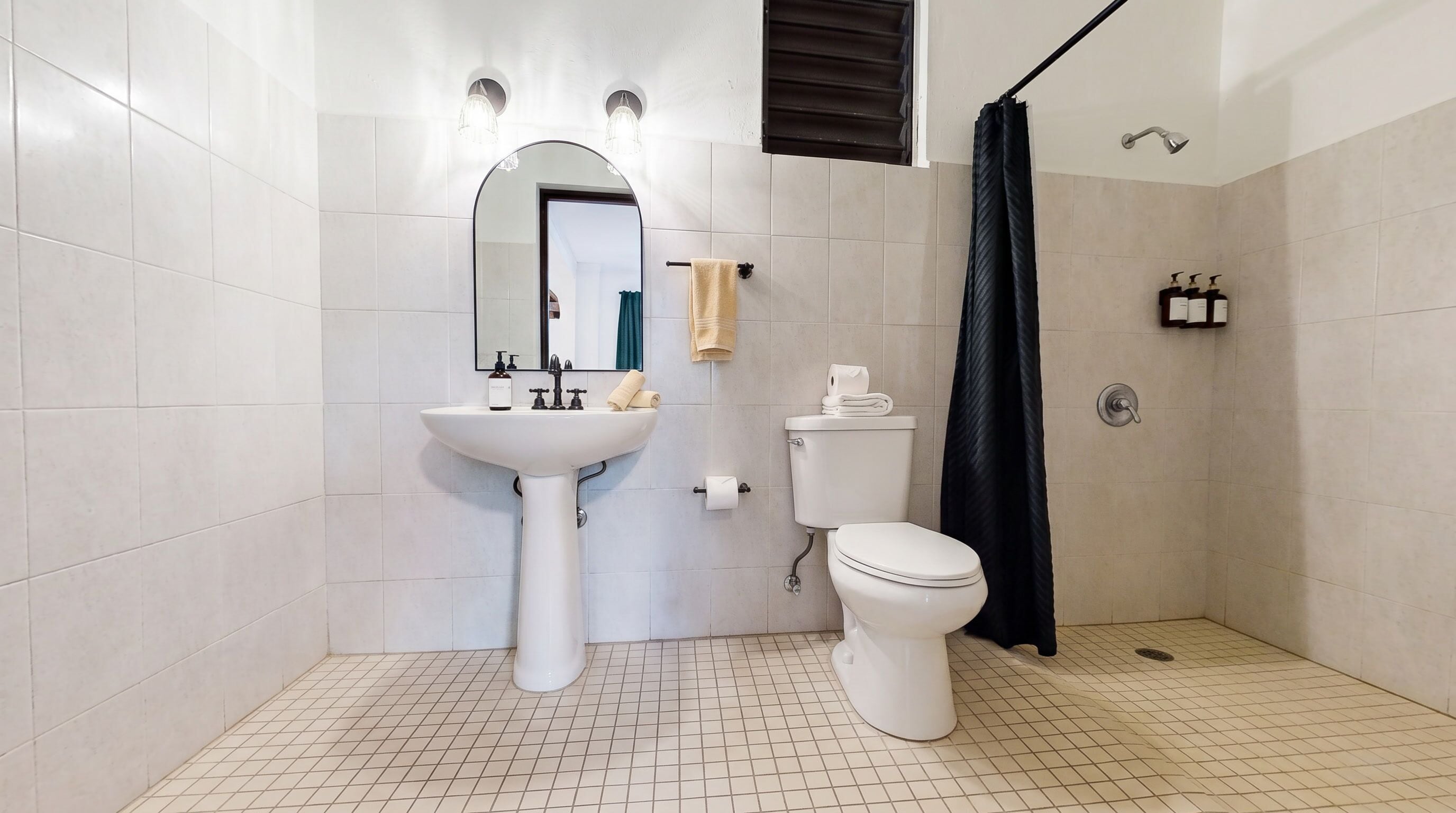 A bathroom with a white sink, toilet, and shower curtain.