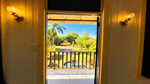 A doorway leading to a balcony with a view of a garden, a pool, and a yellow building. - El Oasis Hotel (Aguada)