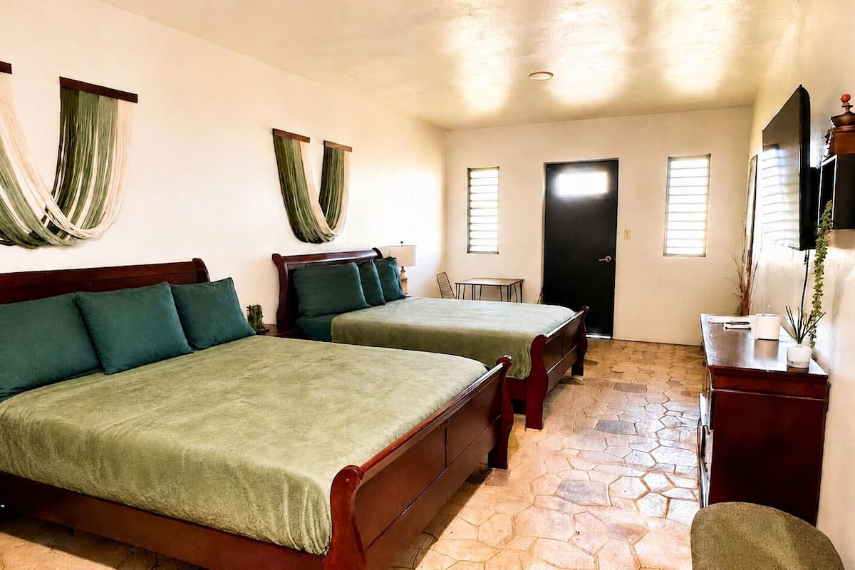 A room with two wooden beds, a desk, a chair, and a small table.