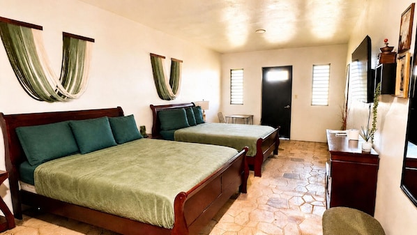 A room with two wooden beds, a desk, a chair, and a small table. - El Oasis Hotel (Aguada)
