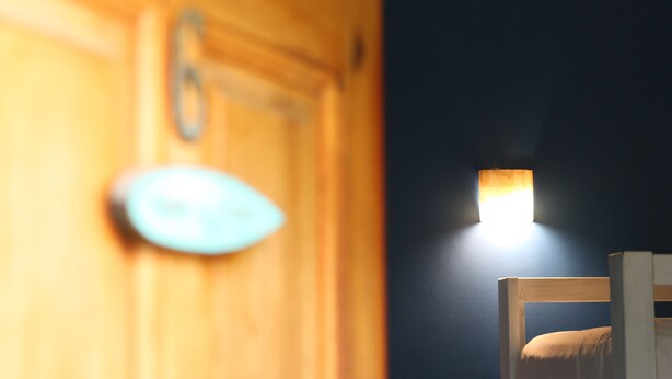 A room with a bed, a wooden wardrobe, and a wall-mounted light fixture. - Experiencia Surf Camp (Brisas de Zicatela)