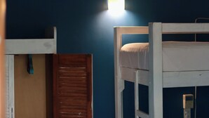 A bunk bed room with a wall-mounted light fixture. - Experiencia Surf Camp (Brisas de Zicatela)