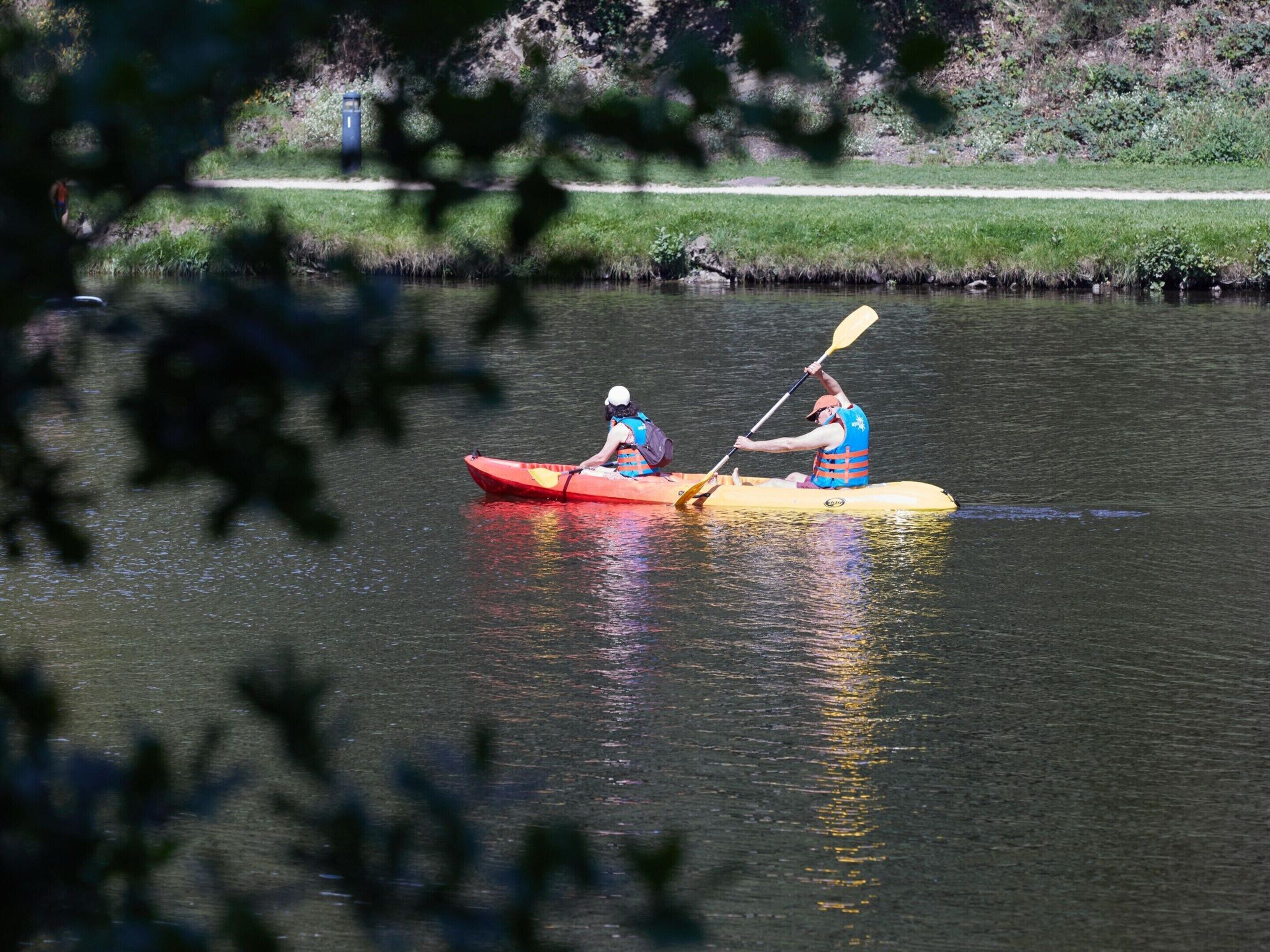 Two people kayaking on a calm river.