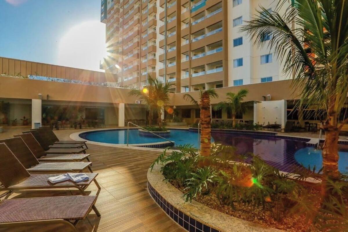 A hotel pool area with sun loungers and palm trees.