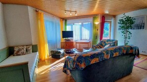 A cozy room with a large bed, a television, and a desk with a computer. - Schöne, große, barrierefreie Ferienwohnung, ruhig, idyllisch, familienfreundlich (Todtmoos)