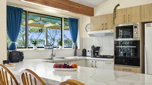 A modern kitchen with a large island, a built-in oven, and a refrigerator. - Azimuth – Family Retreat with Sauna, Garden & Scenic Views (Wentworth Falls)