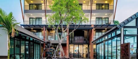 Un edificio moderno con un patio central, ventanas amplias y un árbol.