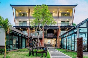 A modern building with a central courtyard, large windows, and a tree. - Momo Hotel (Chiang Mai)