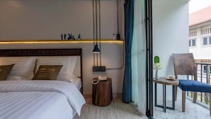 Quarto de hotel com cama, mesa de cabeceira, abajur e vista para a varanda.