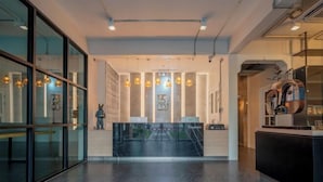 Uma área de recepção moderna com balcão de mármore, iluminação pendente e vista para o exterior.