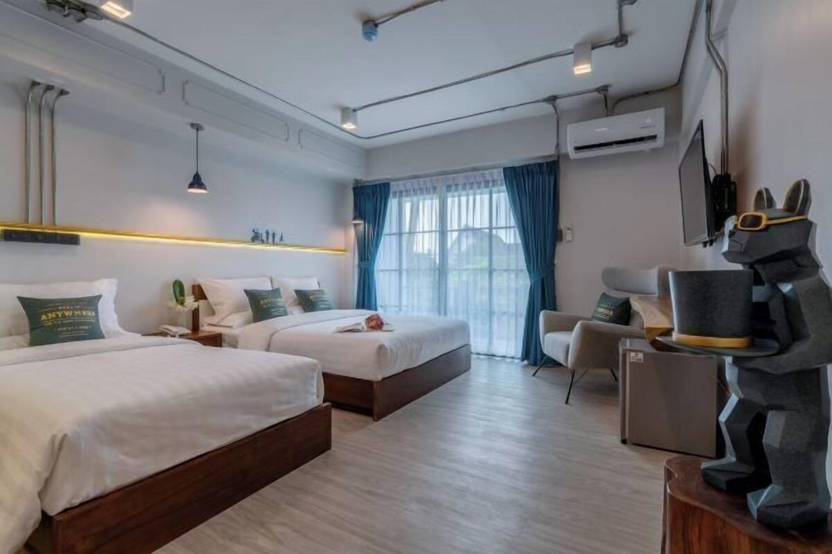 Ett hotellrum med två sängar, ett skrivbord, en stol och en TV.