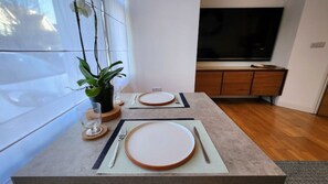 Enjoy a meal in this stylish dining area with a large window, potted plant, and sleek entertainment unit.