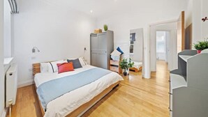 Un dormitorio moderno con una cama grande, un armario, un escritorio y una planta en maceta.