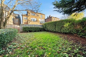 Enjoy a serene yard with a lush lawn, hedge, and trees, surrounded by a traditional brick home.