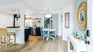 A modern kitchen with a dining area, wooden flooring, and a large mirror on the wall.