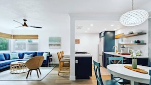 A modern living room with a sofa, chairs, and a dining area with a table and chairs.