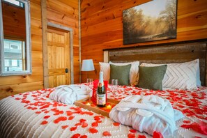 Una habitación de cabaña de madera con una cama, una botella de champán y una bandeja con vasos.