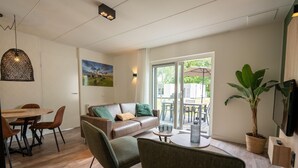 Una sala de estar moderna con un sofá, sillas, una mesa de comedor y un ventanal con vistas al exterior.