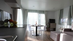 A modern living room with a dining area, a sofa, and a TV. - Comfortable Air-conditioned Chalet in Limburg (Gulpen)