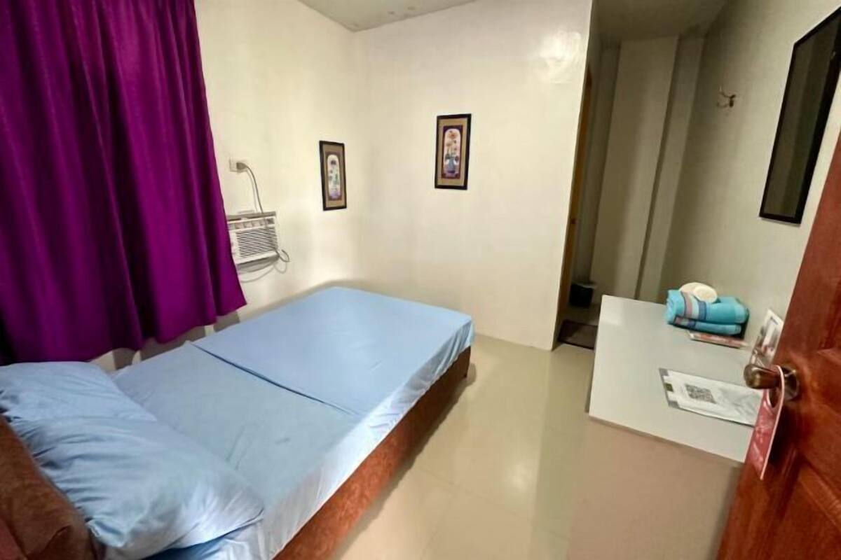 A room with a bed, a desk, a chair, and a door.