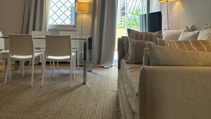 Une pièce avec un plafond en bois, un canapé, une table à manger avec des chaises et une fenêtre avec des rideaux.