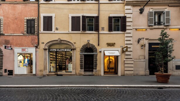 Une vue de rue d’un immeuble abritant un magasin appelé « Hype Clothing » et un autre magasin dont l’enseigne indique « CREED ».