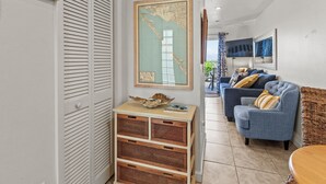 Een woonkamer met een blauwe bank, een houten kast en een kaart aan de muur.