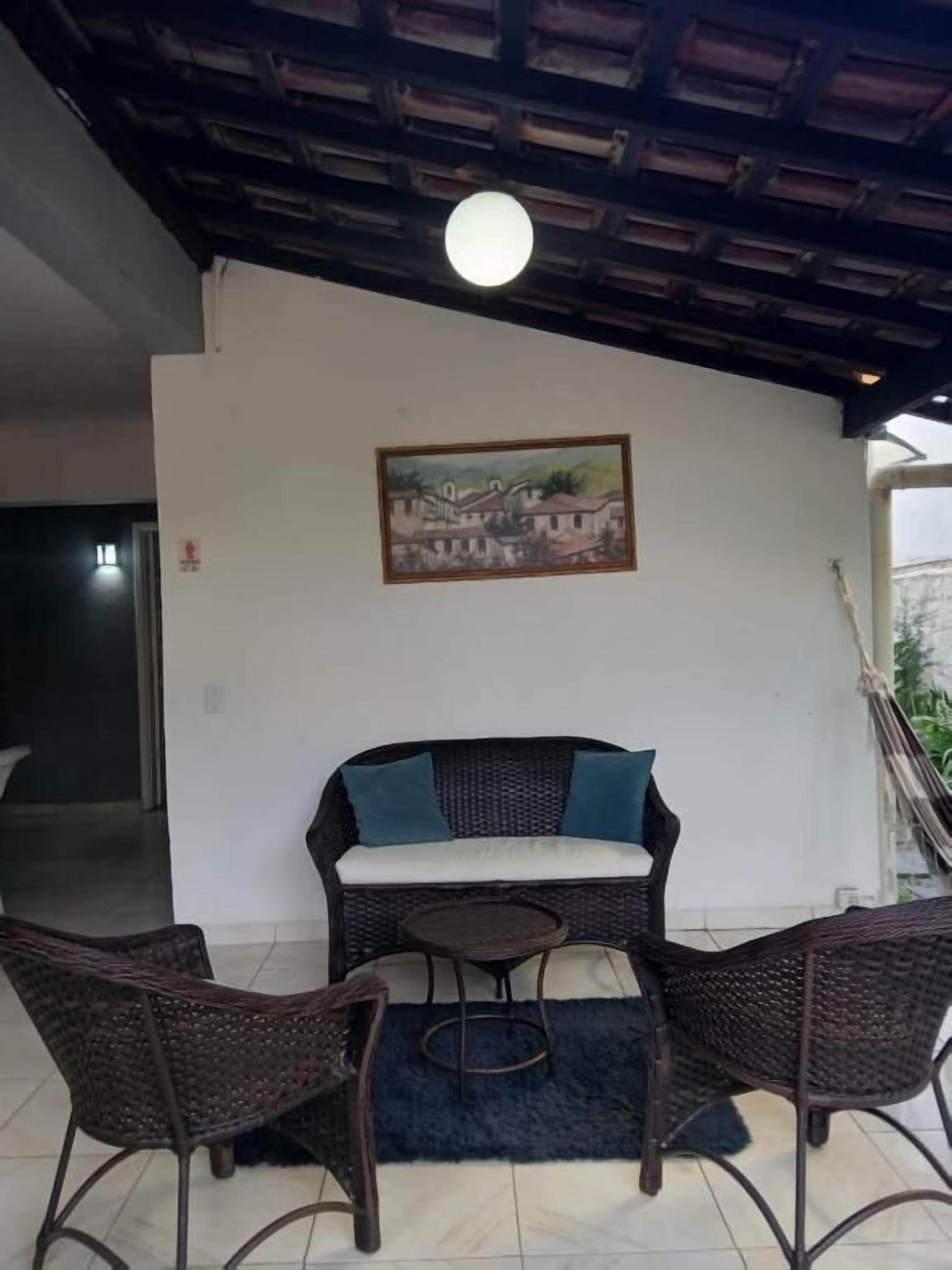 A covered outdoor seating area with wicker furniture and a painting on the wall.
