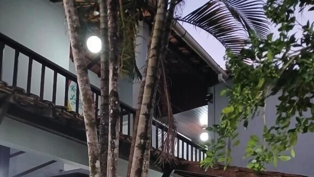 Un bâtiment à deux étages doté d’un espace extérieur couvert, d’un escalier et d’une table à manger avec des chaises.