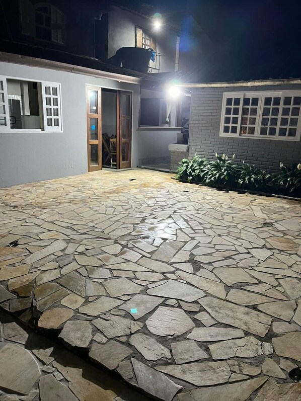 A stone-tiled patio with a wooden door and a small garden area. - Recanto da Luísa (Paraty)