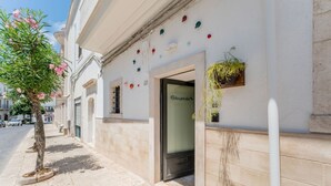 Un edificio con una puerta que indica 'Relax perdue', una planta en maceta y un árbol con flores rosadas.