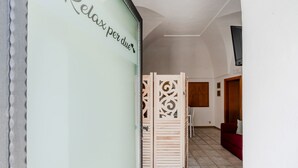 Un pasillo con un separador de madera decorativo, un sofá rojo y un suelo de baldosas.