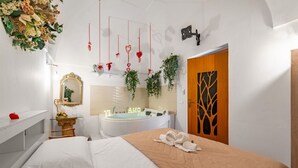 Habitación de hotel con cama, tocador con espejo, bañera y puerta de madera con diseño de árbol.