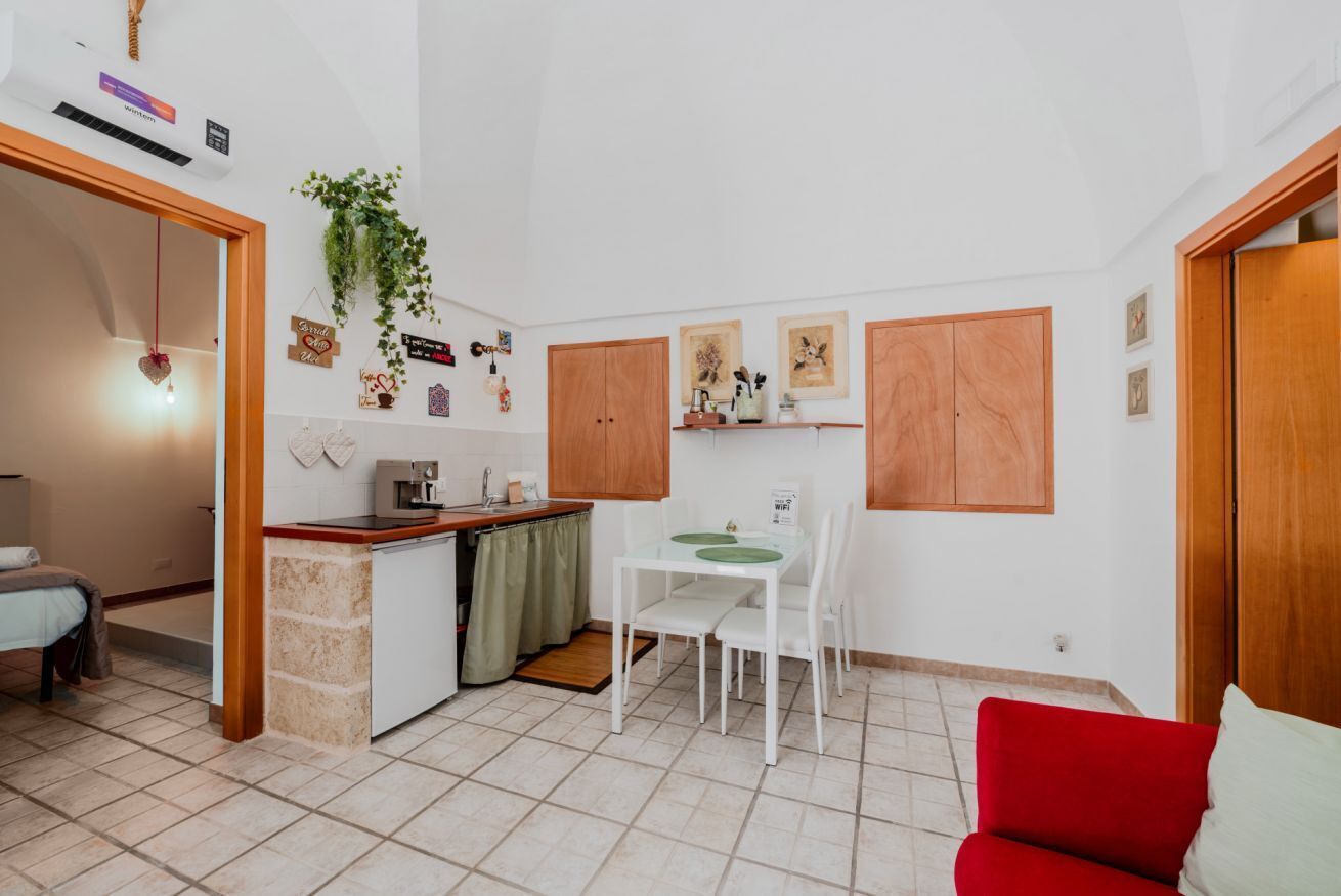 A compact living space with a kitchenette, a dining area, and a red sofa.