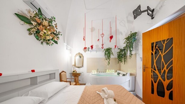 Un dormitorio con cama, tocador con espejo, bañera y puerta de madera con diseño de árbol.