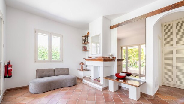 Ein modernes Wohnzimmer mit grauem Sofa, einer Holzbank, einem Kamin und einem großen Fenster.