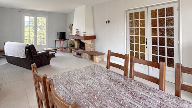 A spacious living area with a dining table, chairs, a fireplace, and a sofa.